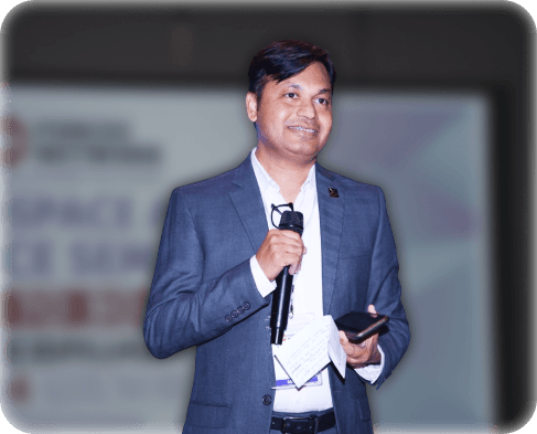 Capt Uday K. Shriwas speaking while holding a microphone on stage