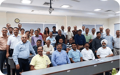 A large group of professionals posing together inside a seminar room