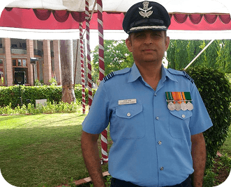 Wg Cdr Pushpendra Dhaka in uniform against a blue backdrop