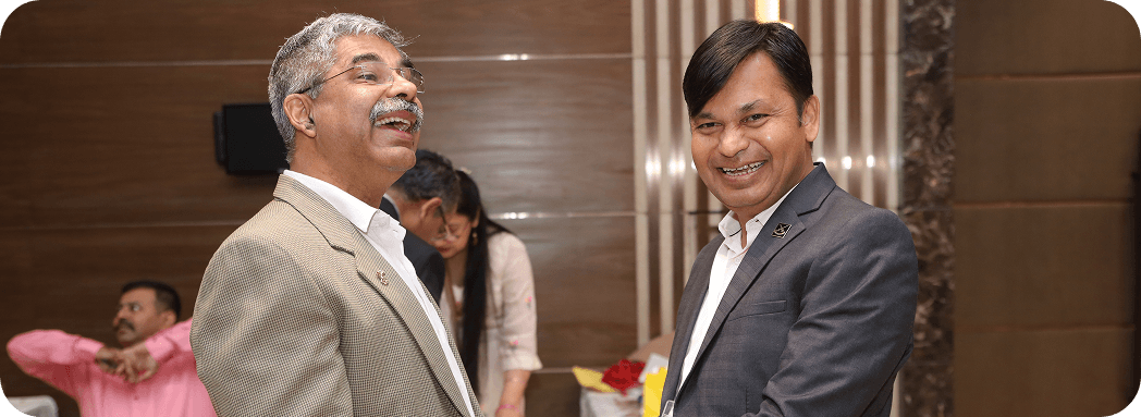 Two professionals smiling together at an indoor networking event
